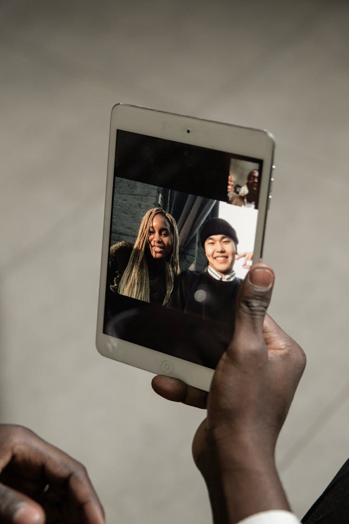 A close-up view of a video call on a tablet showing happy, smiling friends connecting virtually.